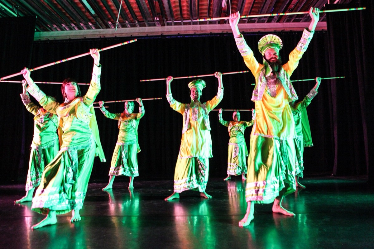Students mid-jump with sticks aloft at the GIDF Gala