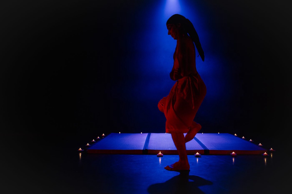 Solo artist silhouetted in red under a blue beam at the GIDF Gala Showcase