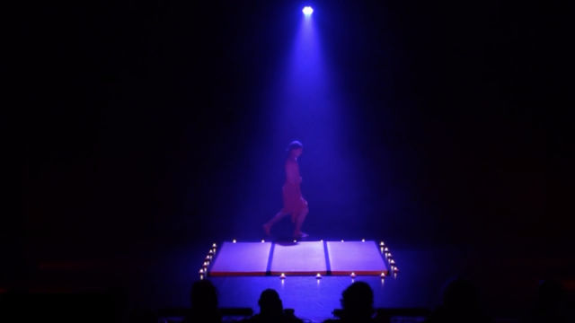 Julien on a candle-lit platform under a single spotlight