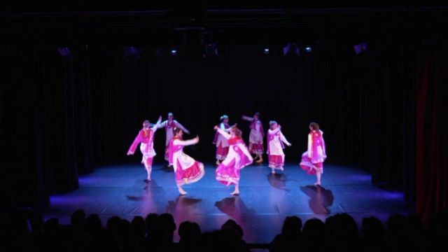 A Bhangra group moving together across the stage