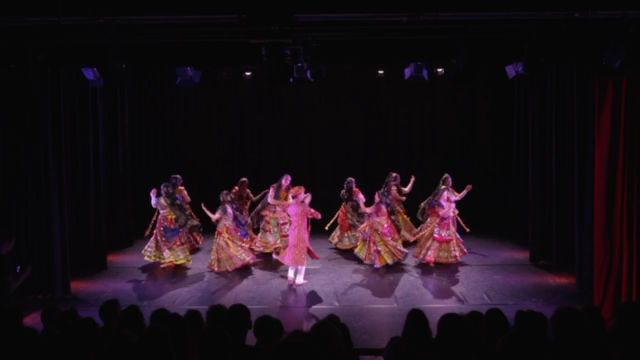 A line of dancers in mirrored folk costume